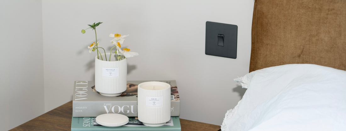 A repurposed Zakiya candle and a Classic Candle with lid on top of books in the bedroom.