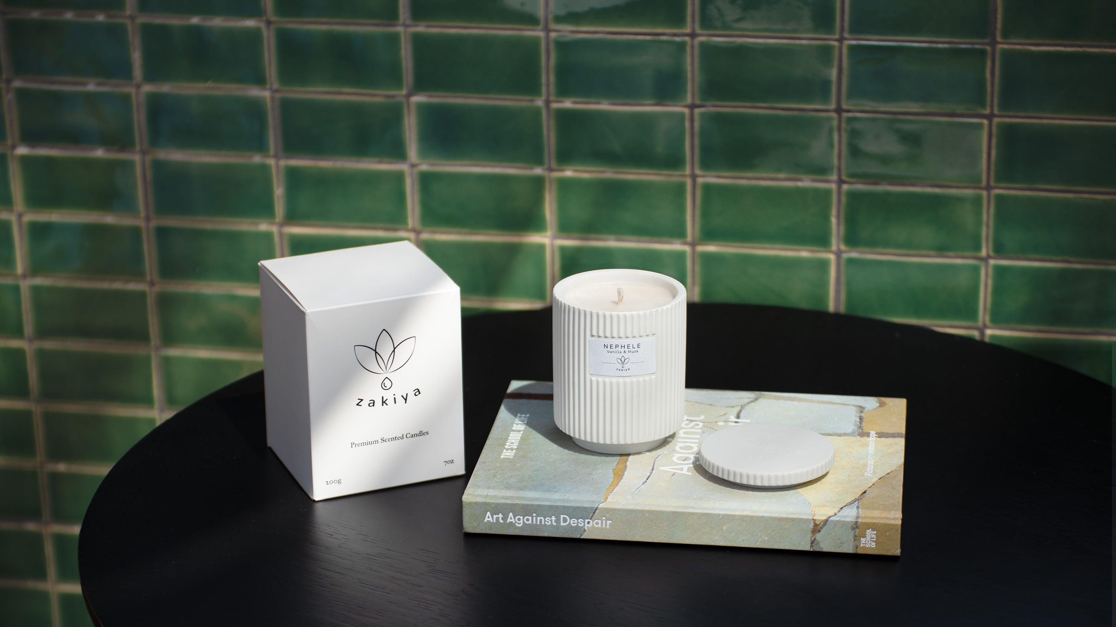 Nephele candle and its cup on top of a book next to the product box.